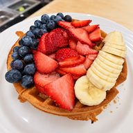 Waffle topped with fresh strawberries, blueberries and sliced banana